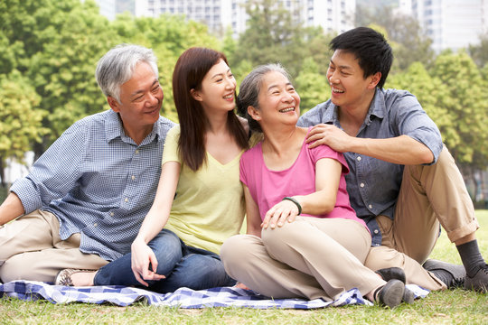 Portrait Of Chinese Parents With Adult Children Relaxing In Park