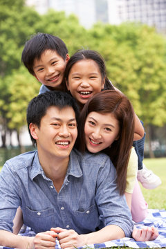 Young Chinese Family Relaxing In Park Together