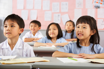 Group Of Students Working At Desks In Chinese School Classroom