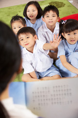 Teacher Reading To Students In Chinese School Classroom