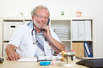 Arzt telefoniert am Schreibtisch