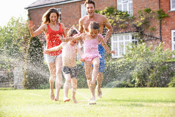 Family Running Through Garden Sprinkler - obrazy, fototapety, plakaty