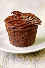 Chocolate cupcake with brown frosting on the plate