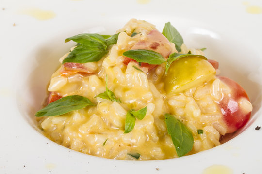 photo of delicious risotto dish with herbs and tomato on white b