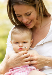Mother Sitting With Baby Girl In Field Of Summer Flowers
