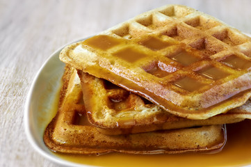 Stack of homemade waffles on the plate with sweet sauce on top