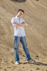 Young man in white shirt and blue jeans standing on the sand