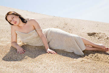 Beautiful brunette  layed down on the sand