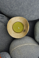 Candle in wooden bowl on stones texture