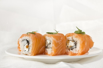 3 Philadelphia rolls on white plate with cloth linen background