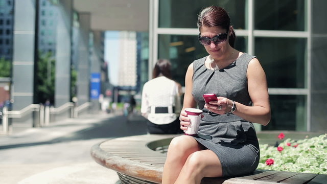 Businesswoman with coffee and smartphone in the city