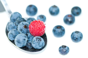 Ein Löffel Heidelbeeren mit einer Himbeere