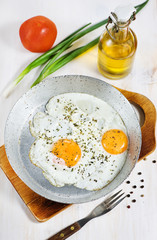 Fried eggs with spice on the old metallic pan