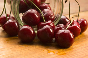 Cherry in glass jar isolated on the wooden background