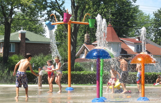 Children running under water spouts