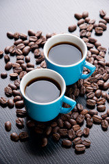 Two espresso cups and roasted coffee beans, vertical shot