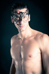 Portrait of young man shirtless against black background.