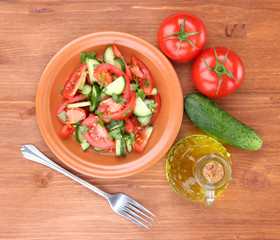Fresh salad with tomatoes and cucumbers on wooden background