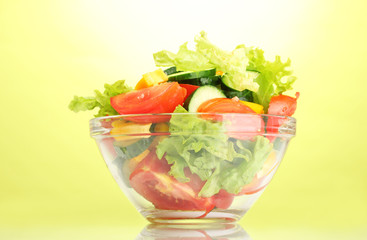 fresh vegetable salad in transparent bowl on green background