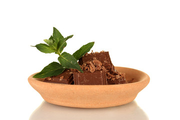 Pieces of chocolate and mint on the clay plate isolated on