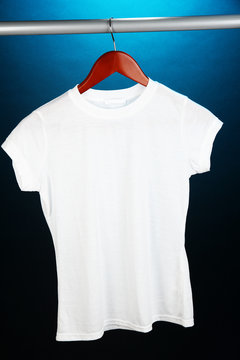 White t-shirt on hanger on blue background