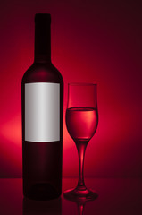 bottle and glass with white wine on red background
