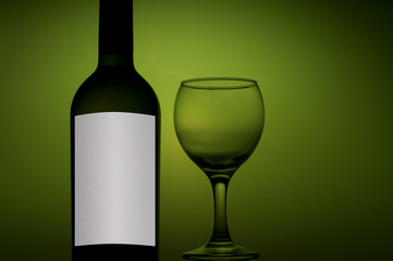 bottle and glass with white wine on green background