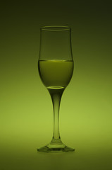A glass of white wine on green background