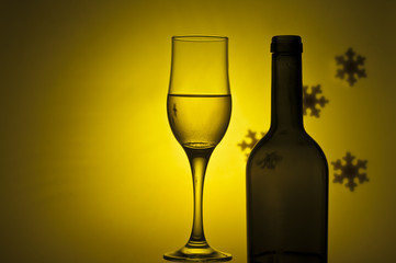 bottle and glass with white wine on yellow background