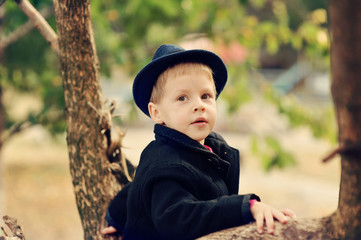 the boy in the autumn wood in a hat and a coat among trees