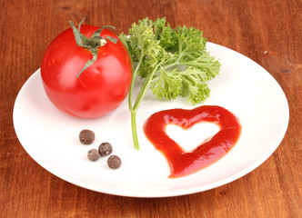 Ripe tomato and spices on plate on wooden table