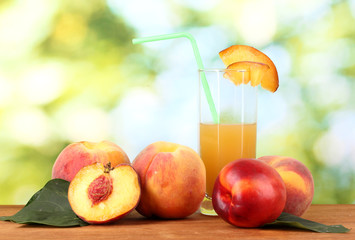 Ripe peaches and juice on wooden table on natural background