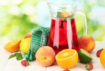 sangria in jar with fruits, on wooden table, on green
