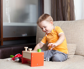 adorable boy playing with wooden building toys at home