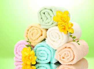 Obraz na płótnie Canvas kolorowe ręczniki i kwiaty na zielonym żółtym tle