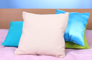 Fototapeta na wymiar bright pillows on bed on blue background