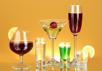 a variety of alcoholic drinks on yellow background