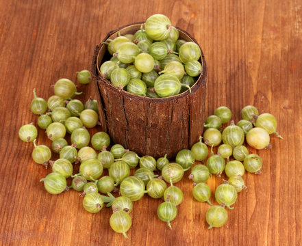 Green gooseberry in wooden cup on wooden background