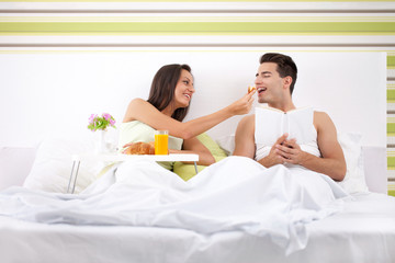 Obraz na płótnie Canvas Młoda i piękna para o śniadanie w łóżku