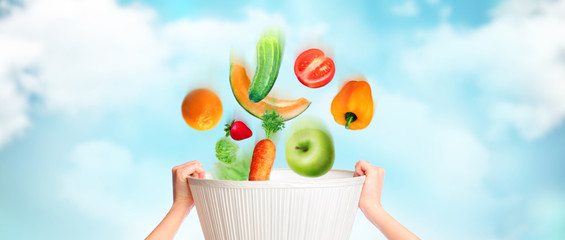 Hands are holding basket against sky background, vegetables, fru