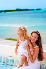 young beautiful woman and her daughter playing at tropical beach