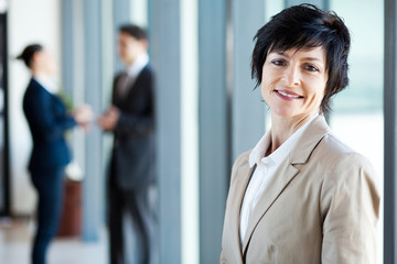 middle aged businesswoman in office with colleagues