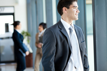 handsome young businessman looking outside office window