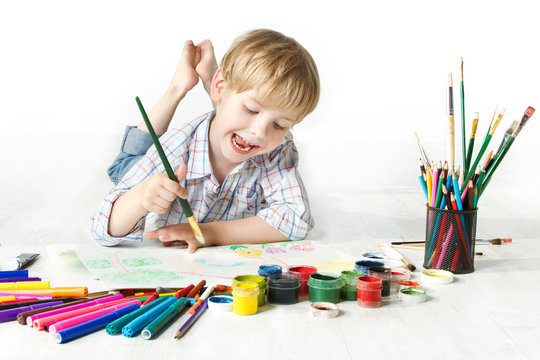 Happy cheerful child drawing with brush in album, a lot of tools