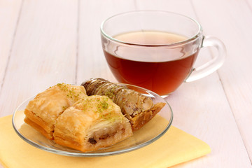 Sweet baklava on plate with tea on wooden background