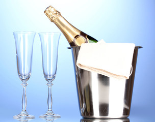 Champagne bottle in bucket with ice and glasses