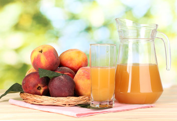 Ripe peaches and juice on wooden table on natural background