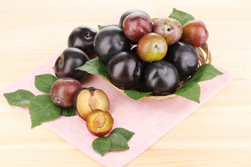 Rip plums on basket on wooden table