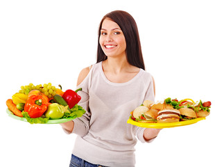 Woman choosing between fruit and hamburger.