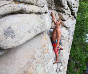 Young male rock climber looking up at the next handhold